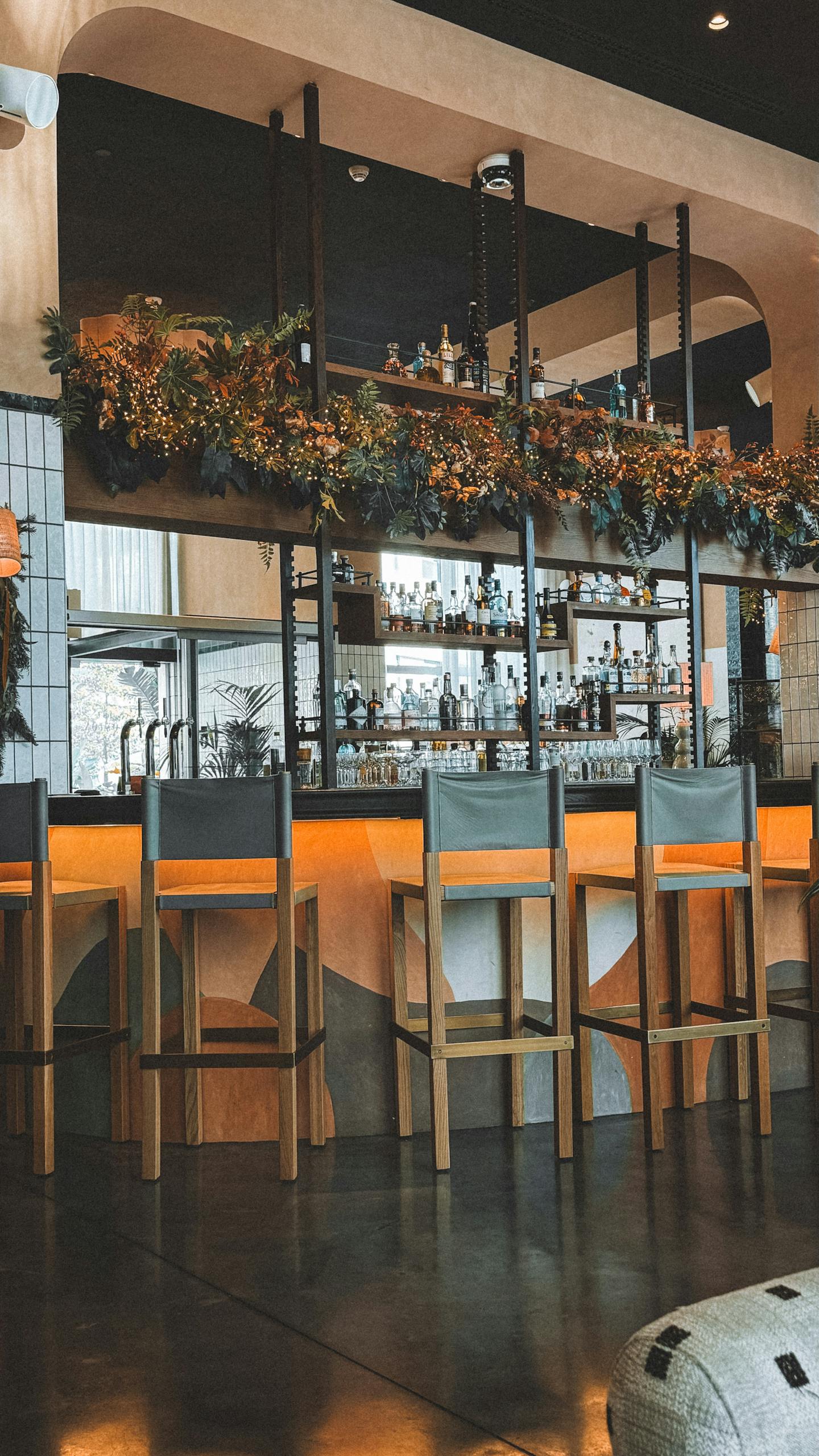 Stylish bar interior with wooden chairs and floral decorations, offering a contemporary ambiance.